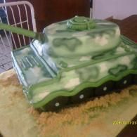 Green camouflage toy tank on a sandy surface with a long barrel and turret.