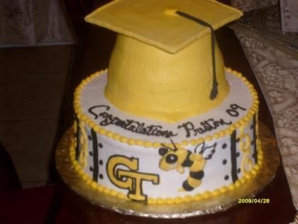 Yellow graduation cake with cap, black-and-gold decorations, and Georgia Tech logo