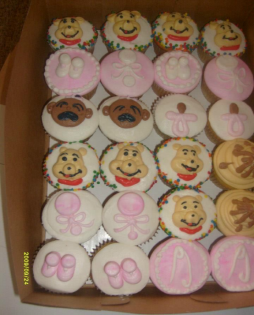 Tray of decorated cupcakes with pink icing and cartoon animal faces arranged in rows