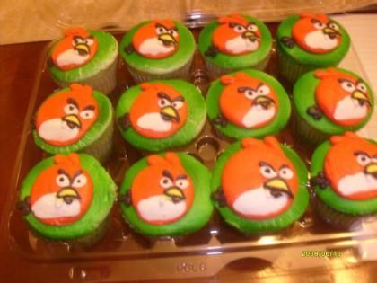 Tray of Angry Birds cupcakes with green frosting and red bird faces in a bakery box