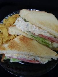 Two triangular sandwich halves on a black plate with chips on the side