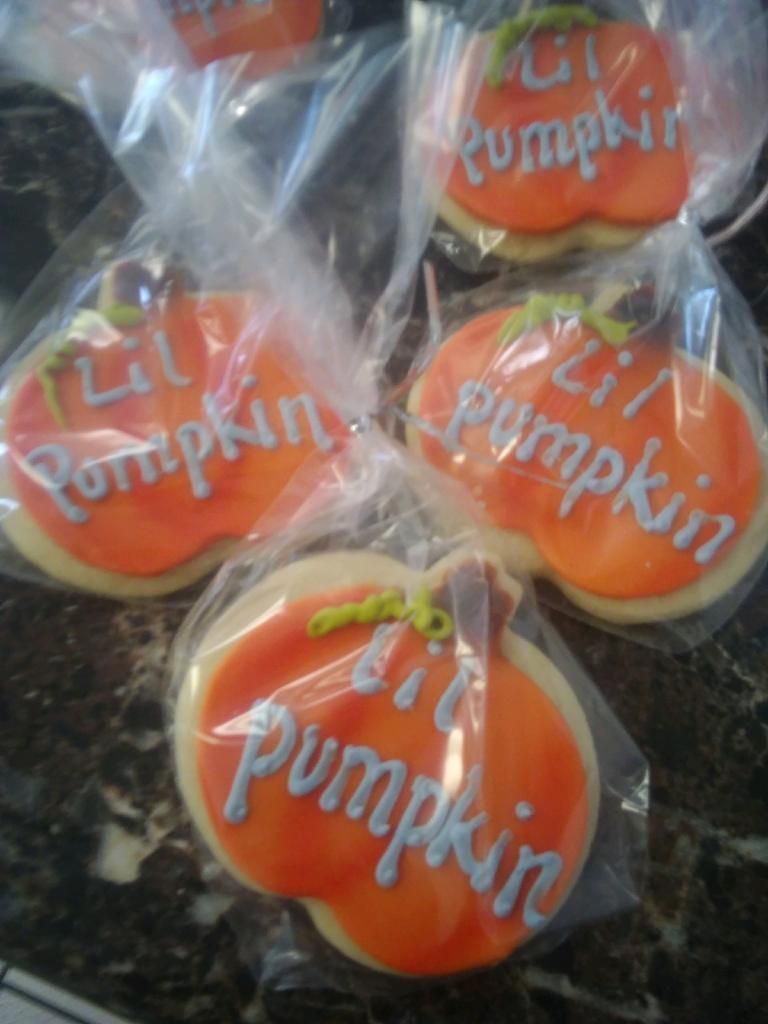 Orange pumpkin-shaped cookies wrapped in clear plastic, stacked together.
