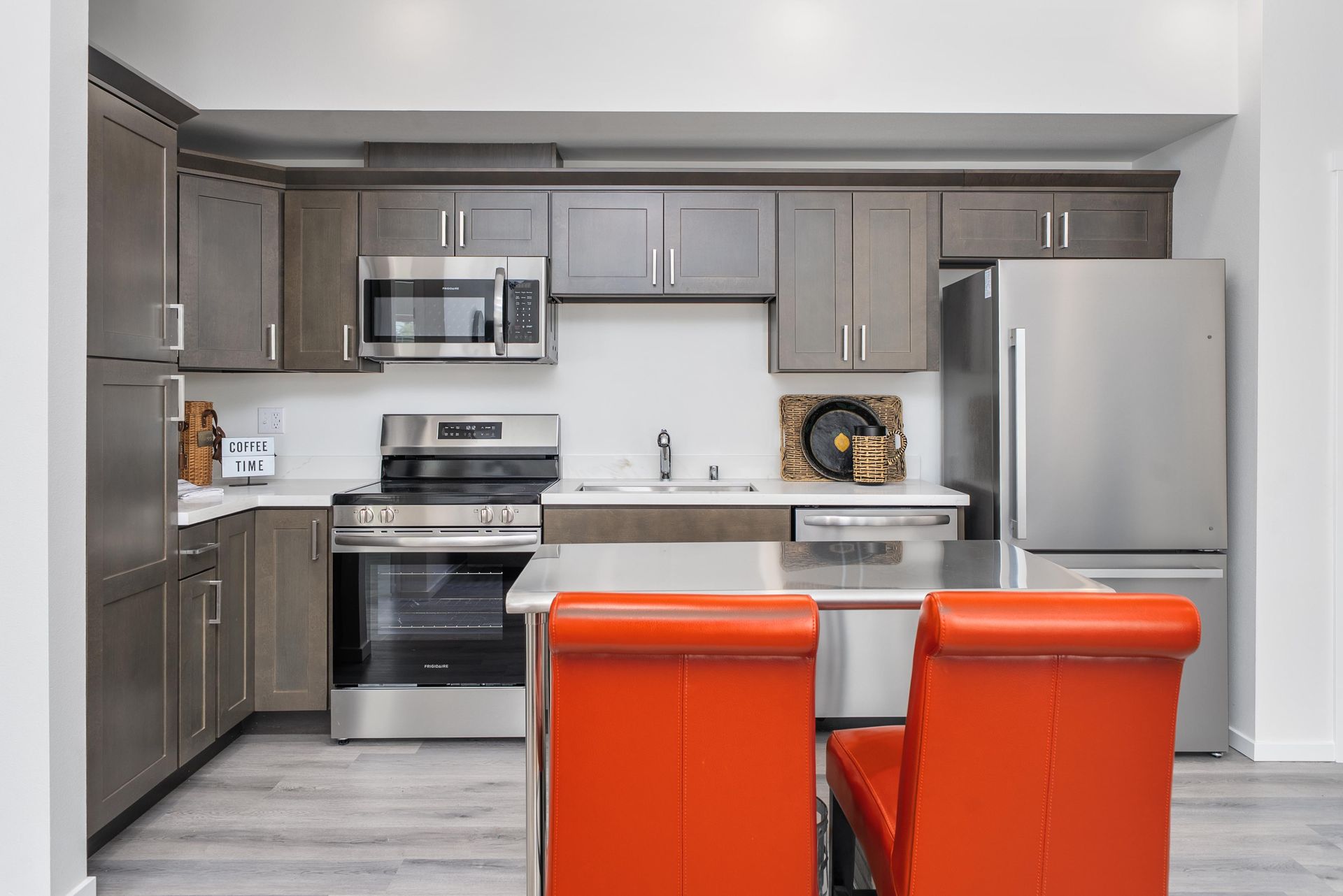 Kitchen with grey cabinets, stainless steel appliances, and red chairs at Blueberry Apartments Port Orchard
