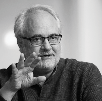 A black and white head shot of Bill Joiner, a white man with white hair, glasses and a beard.