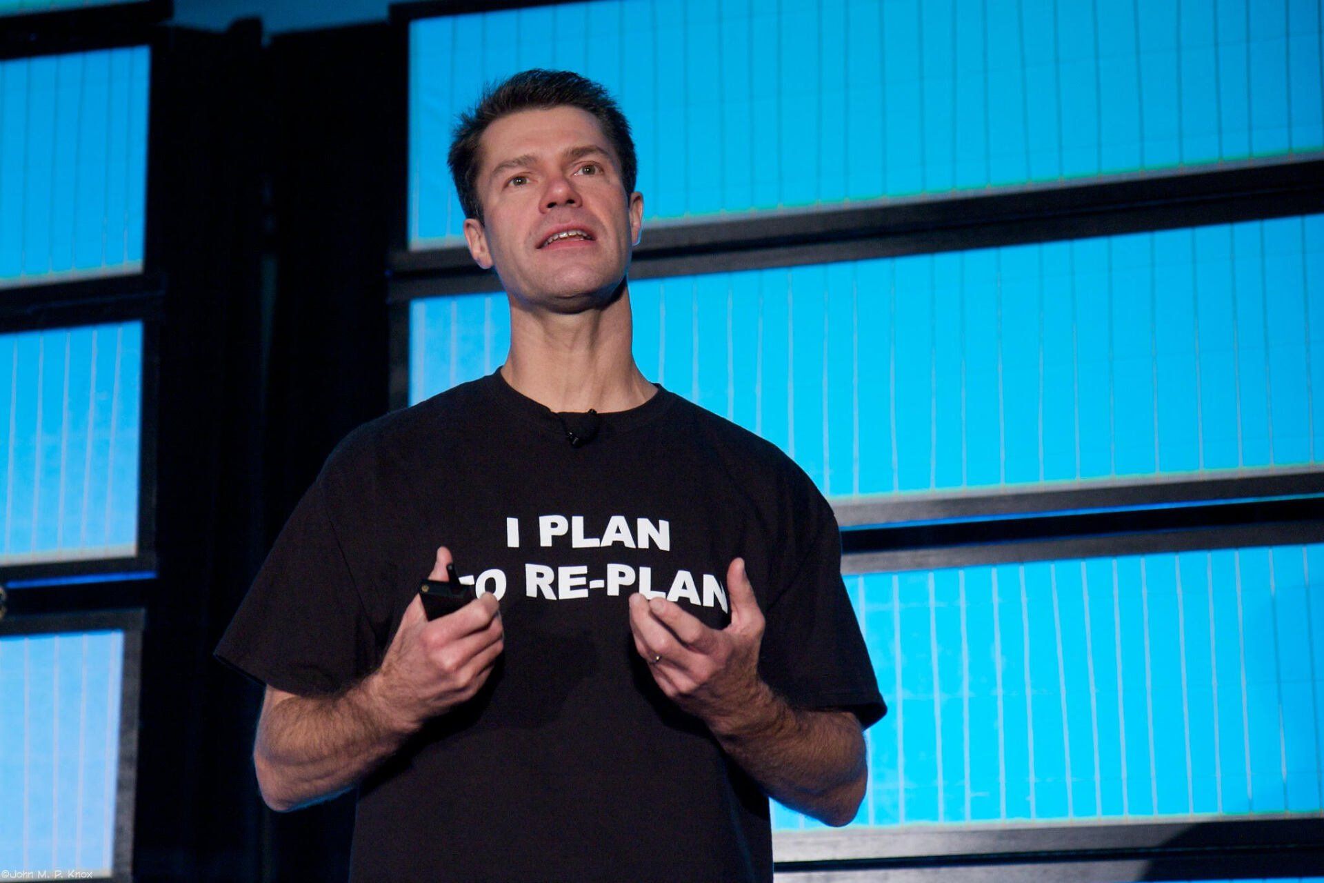 A man wearing a black shirt that says i plan to re-plan