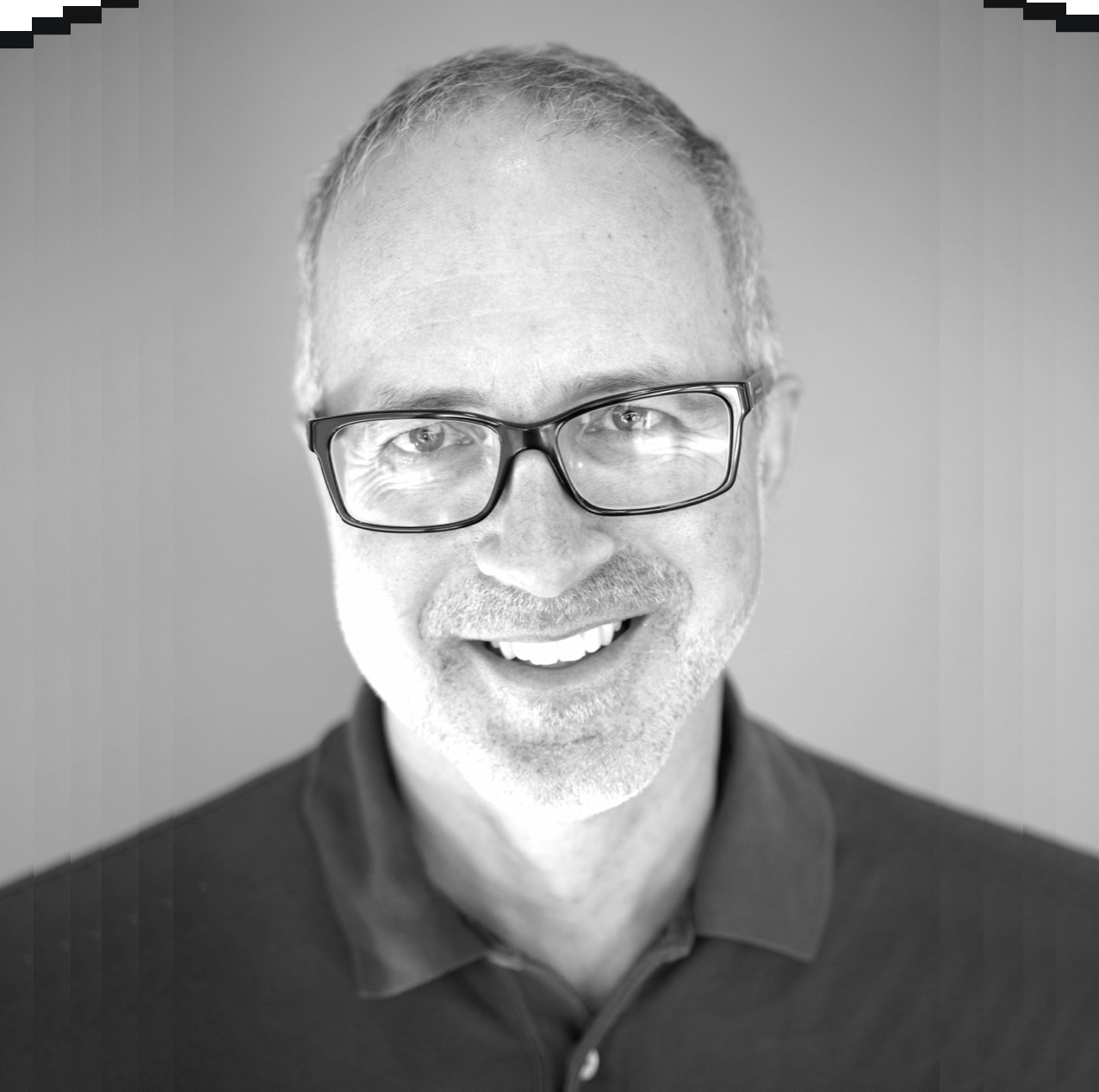 A black and white photo of von rhea, a white man with short silver hair, beard stubble and glasses