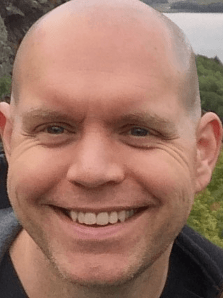 A close up shot of Andy Slain, a bald white man. Andy is grinning from ear to ear.
