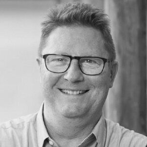 A black and white headshot of Bent Myllerup, a white man with red hair and glasses