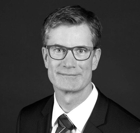 A man in a suit and tie is wearing glasses.