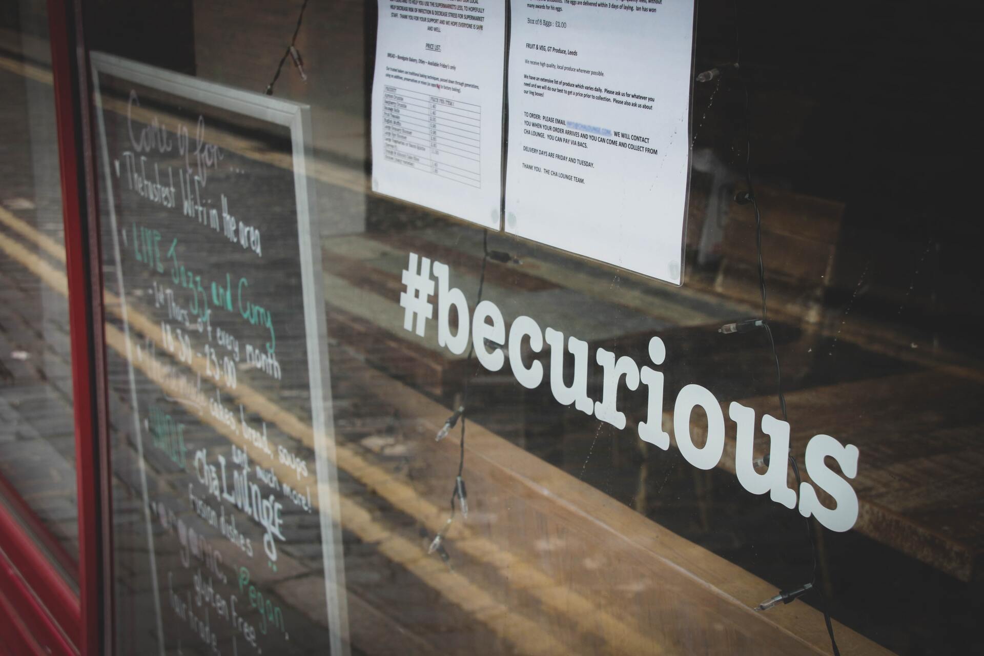 A window with #becurious printed on the glass.