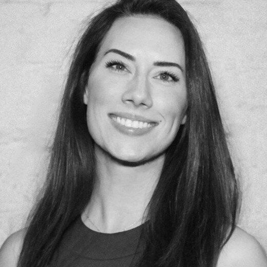 A woman with long hair is smiling in a black and white photo.