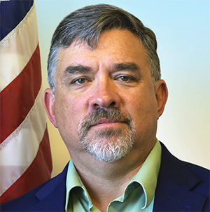 Photo of Dr. Eric Kihn in front of an American flag