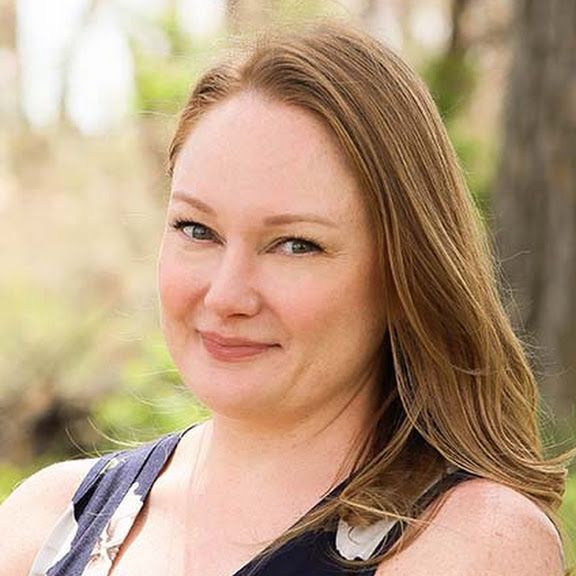 A woman with long brown hair is smiling for the camera.