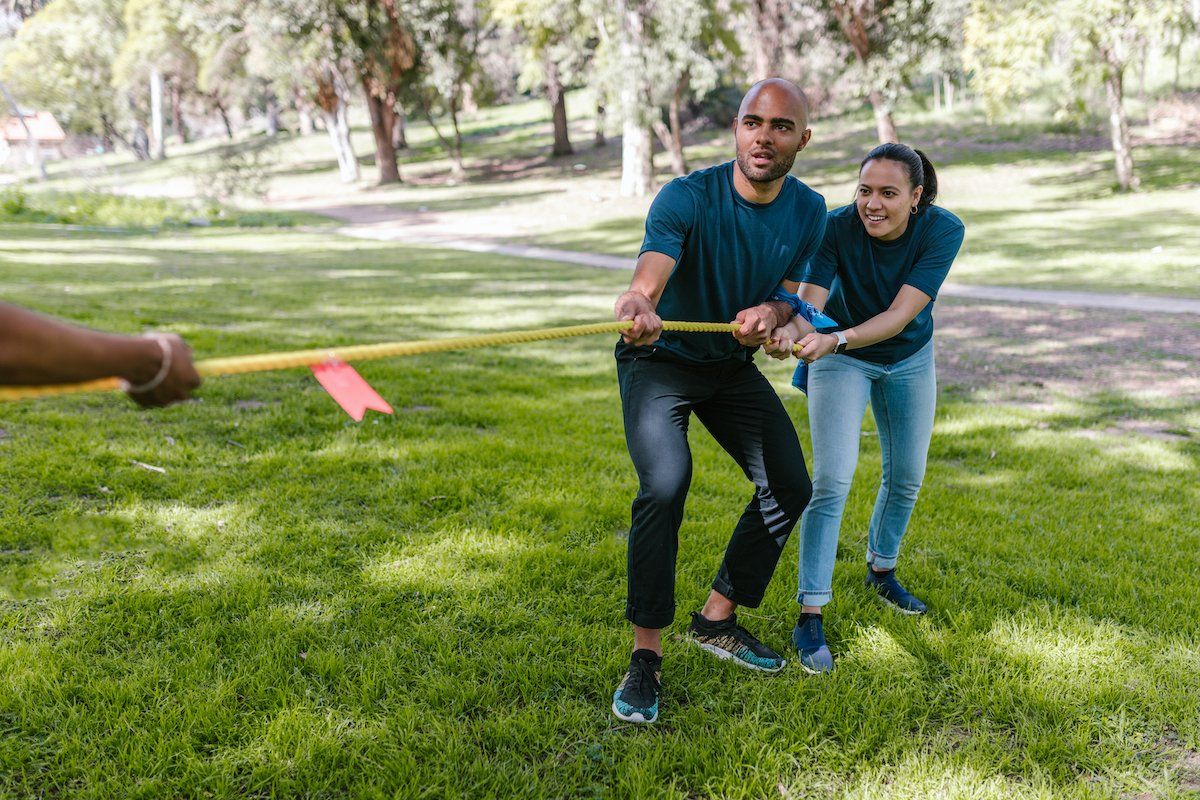 A man and a woman are pulling a rope in a park.