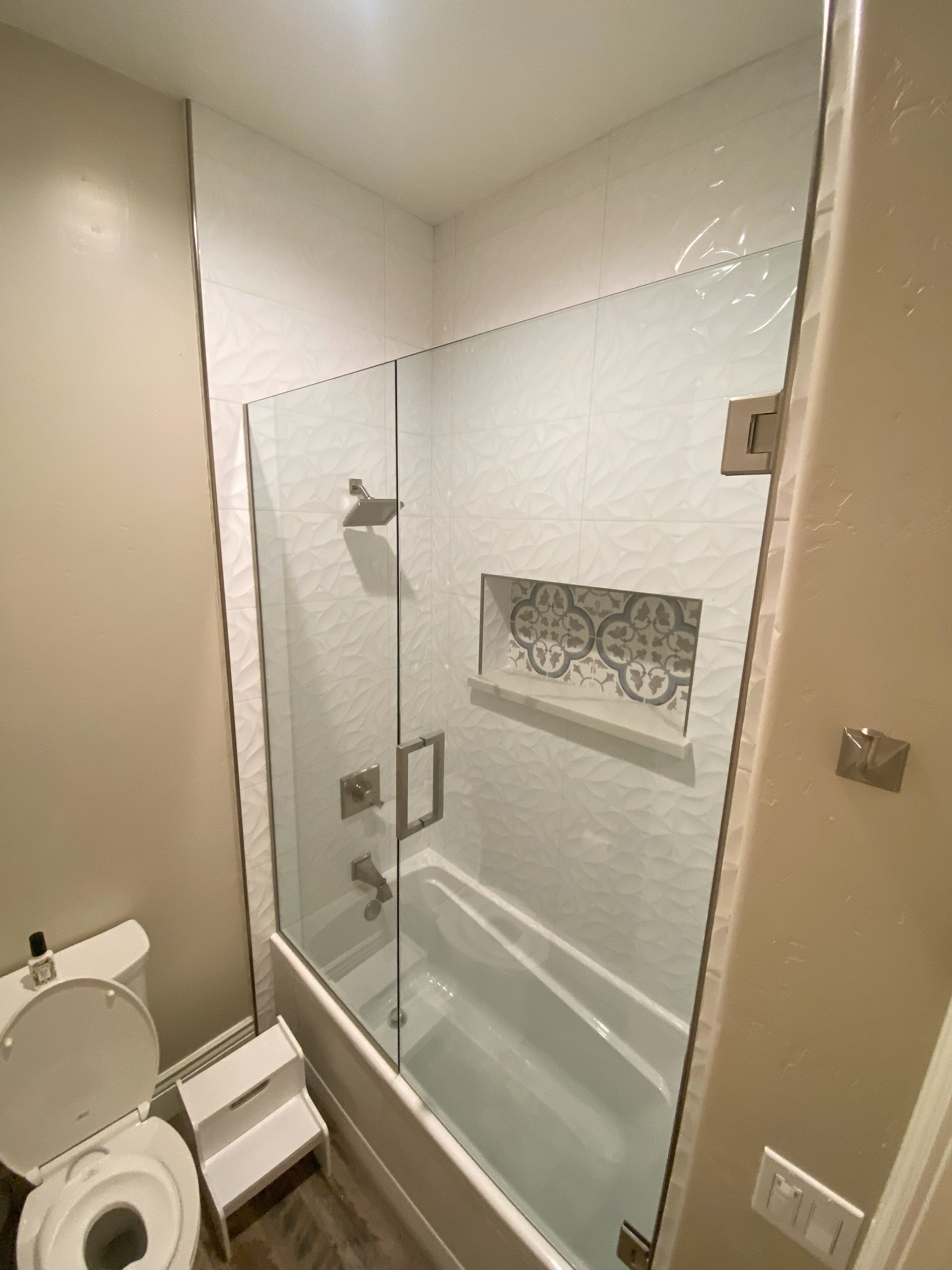 Frameless glass shower with precision stainless steel fittings installed by Glassology