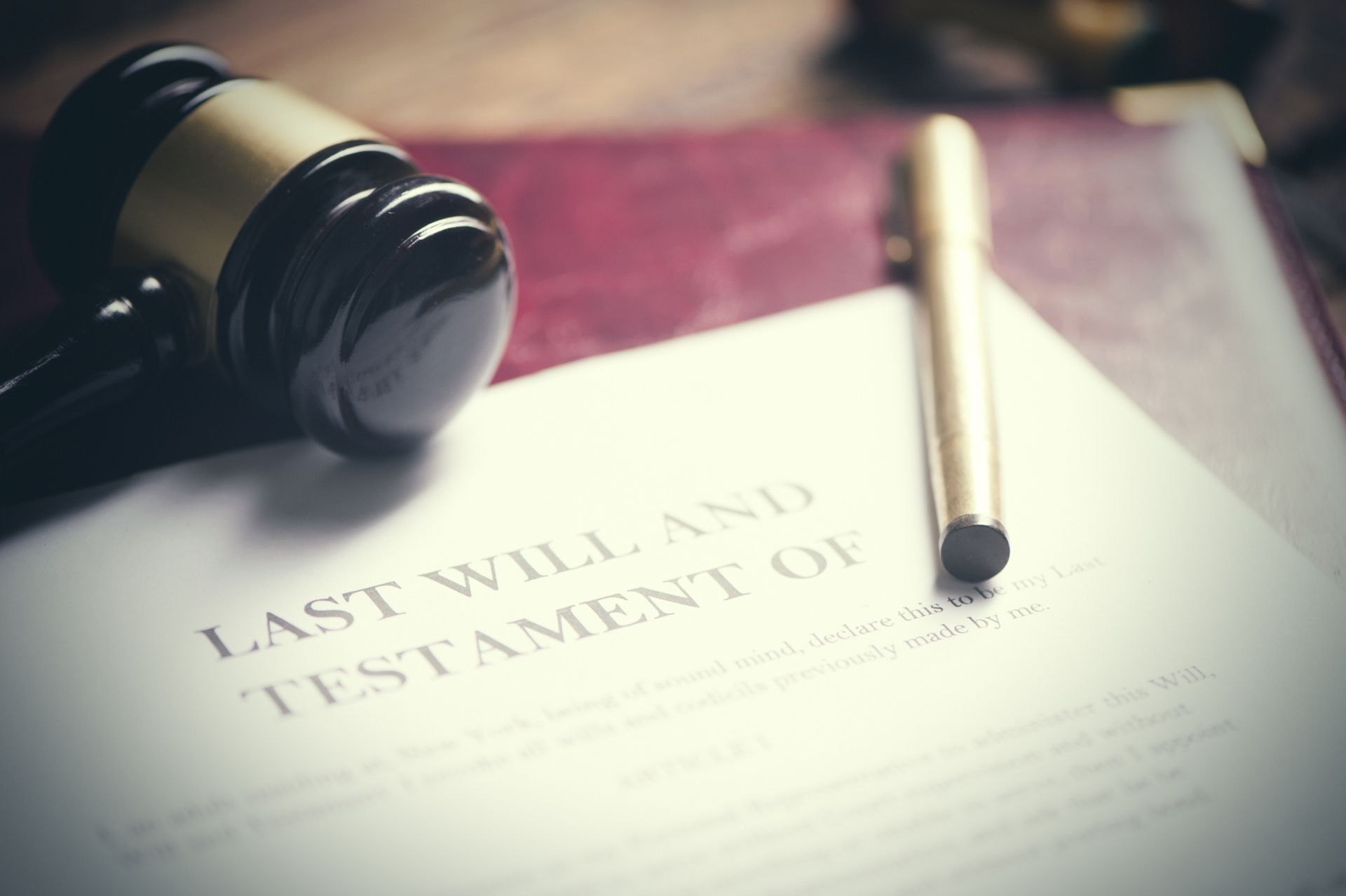 A judge 's gavel is sitting on top of a last will and testament.