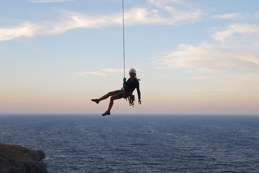 Climber being lowered on a rope above the sea