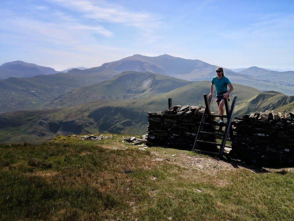 Runner heading over a stye with mountains in the background