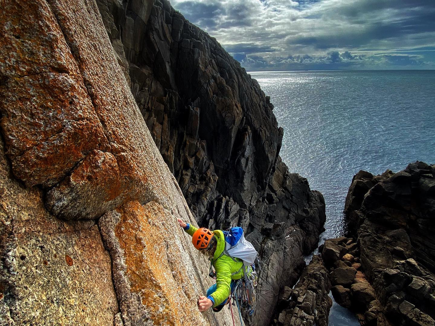 Climber on sea cliffs ascending a slab