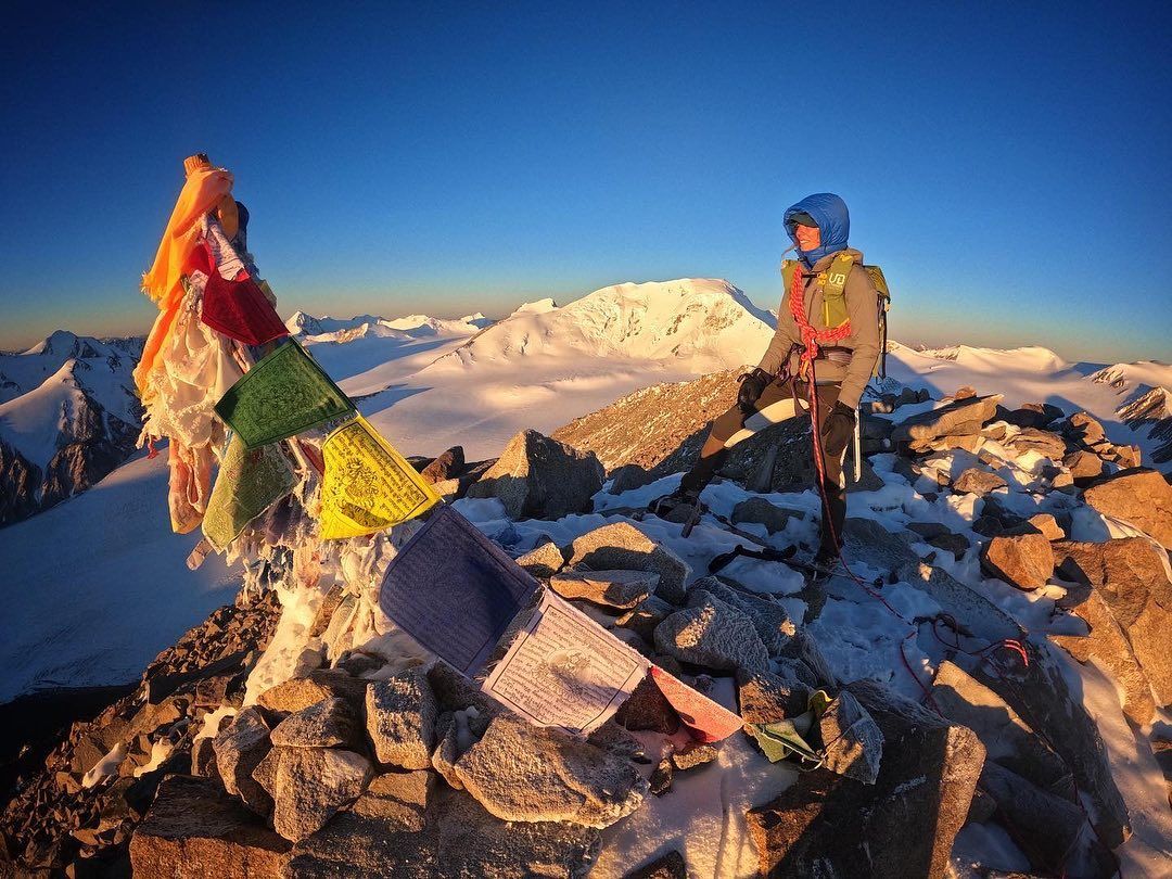 Summit pose with prayer flags in Mongolia