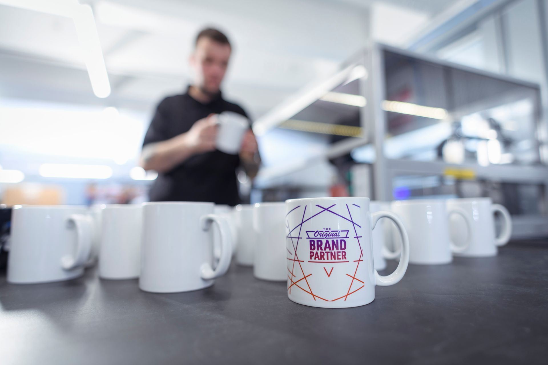 Worker inspecting printed mugs in a fabric printing factory.