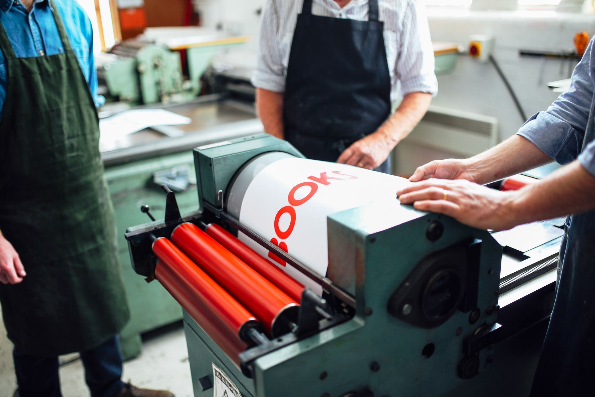 Craftspeople being shown how to use a letterpress machine.