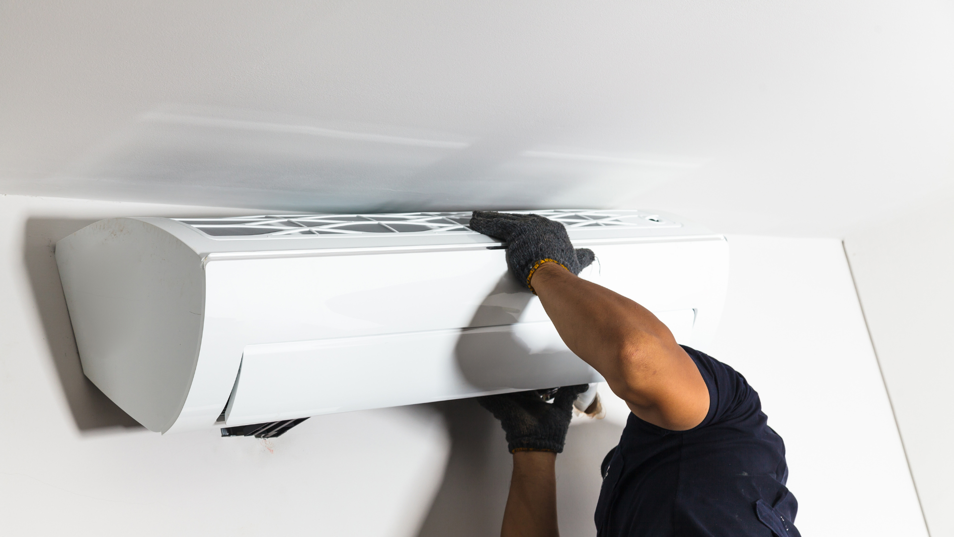 A man is installing an air conditioner on the wall.