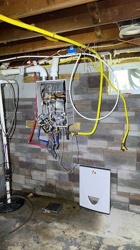 A water heater is hanging from the ceiling in a basement.