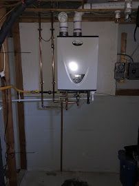 A water heater is hanging from the ceiling in a basement.