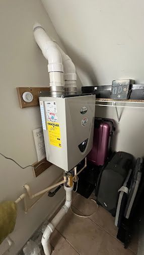 A water heater is mounted to the wall in a room with luggage.
