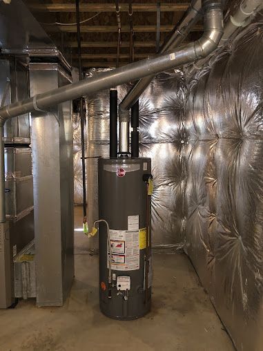 A water heater is sitting in a room with a lot of pipes.