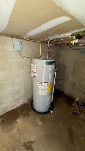 A water heater is sitting in a basement next to a wall.