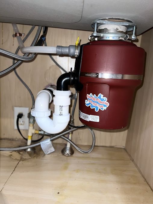 A red garbage disposal is under a sink in a kitchen.