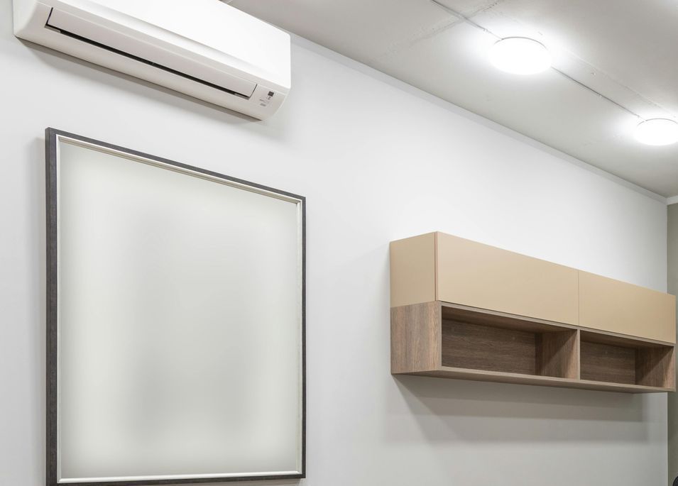 A room with a wall mounted air conditioner and a picture on the wall.