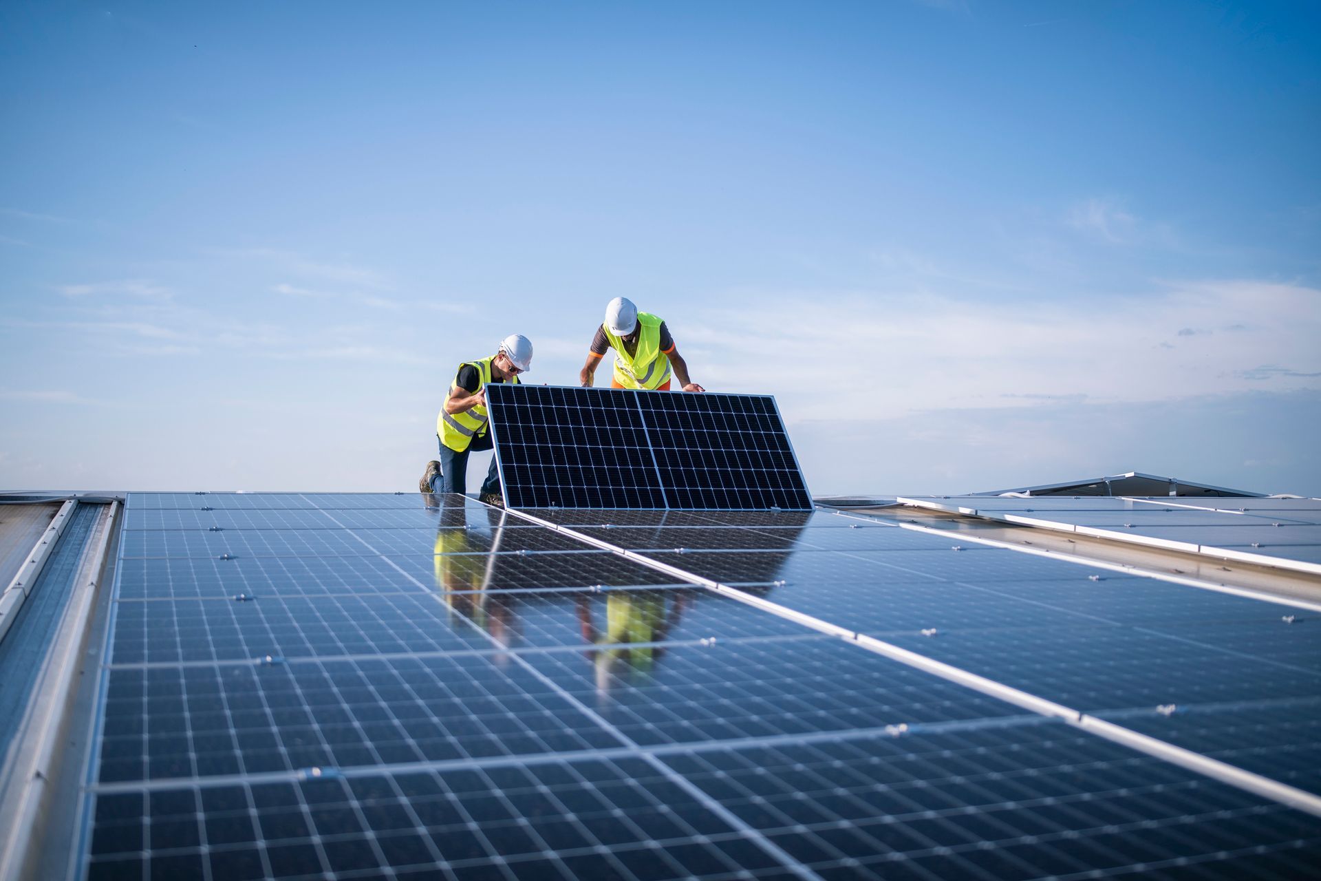 Installers fitting solar panels on a rooftop solar system