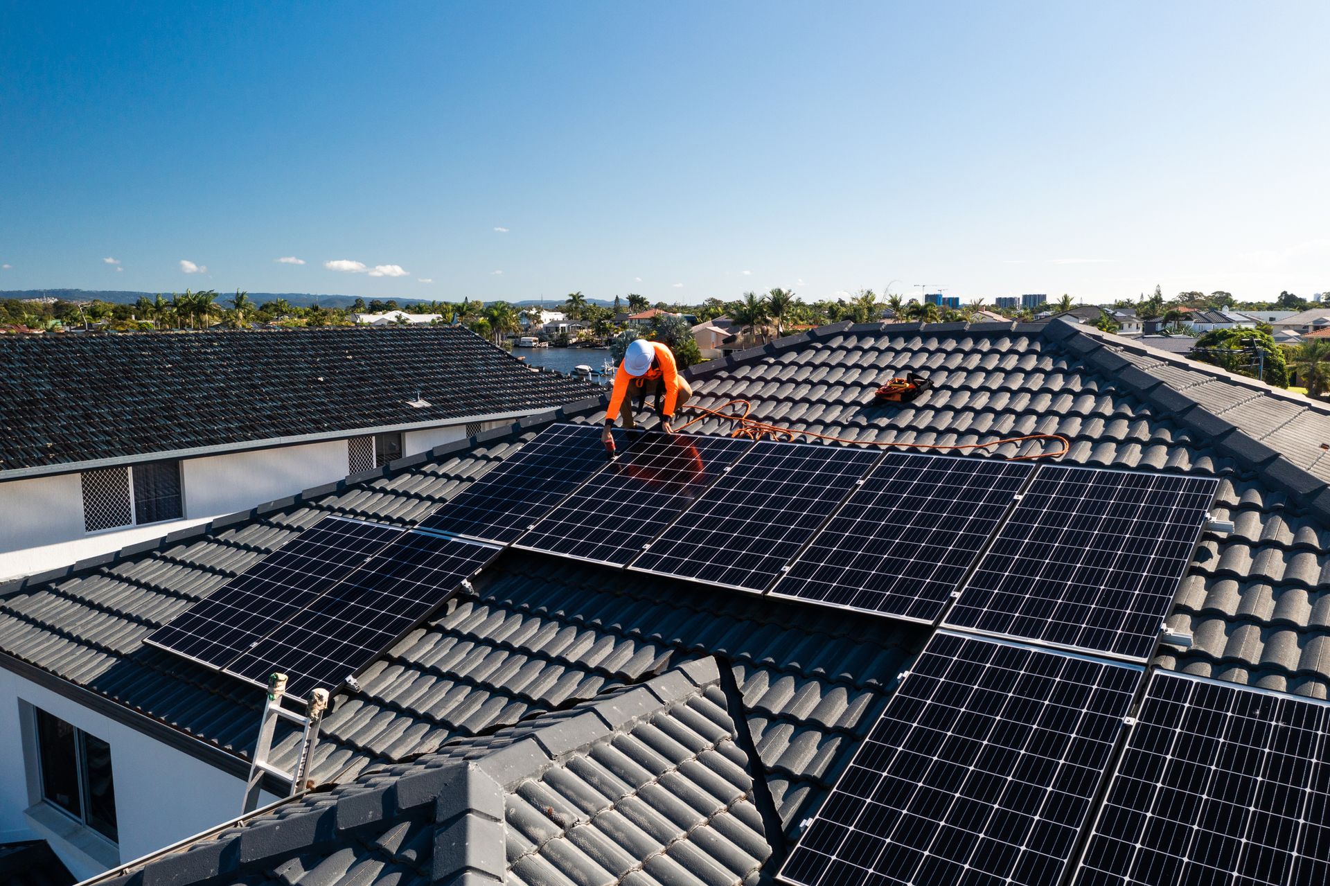 Solar panel installation on a rooftop by two workers on a sunny day.