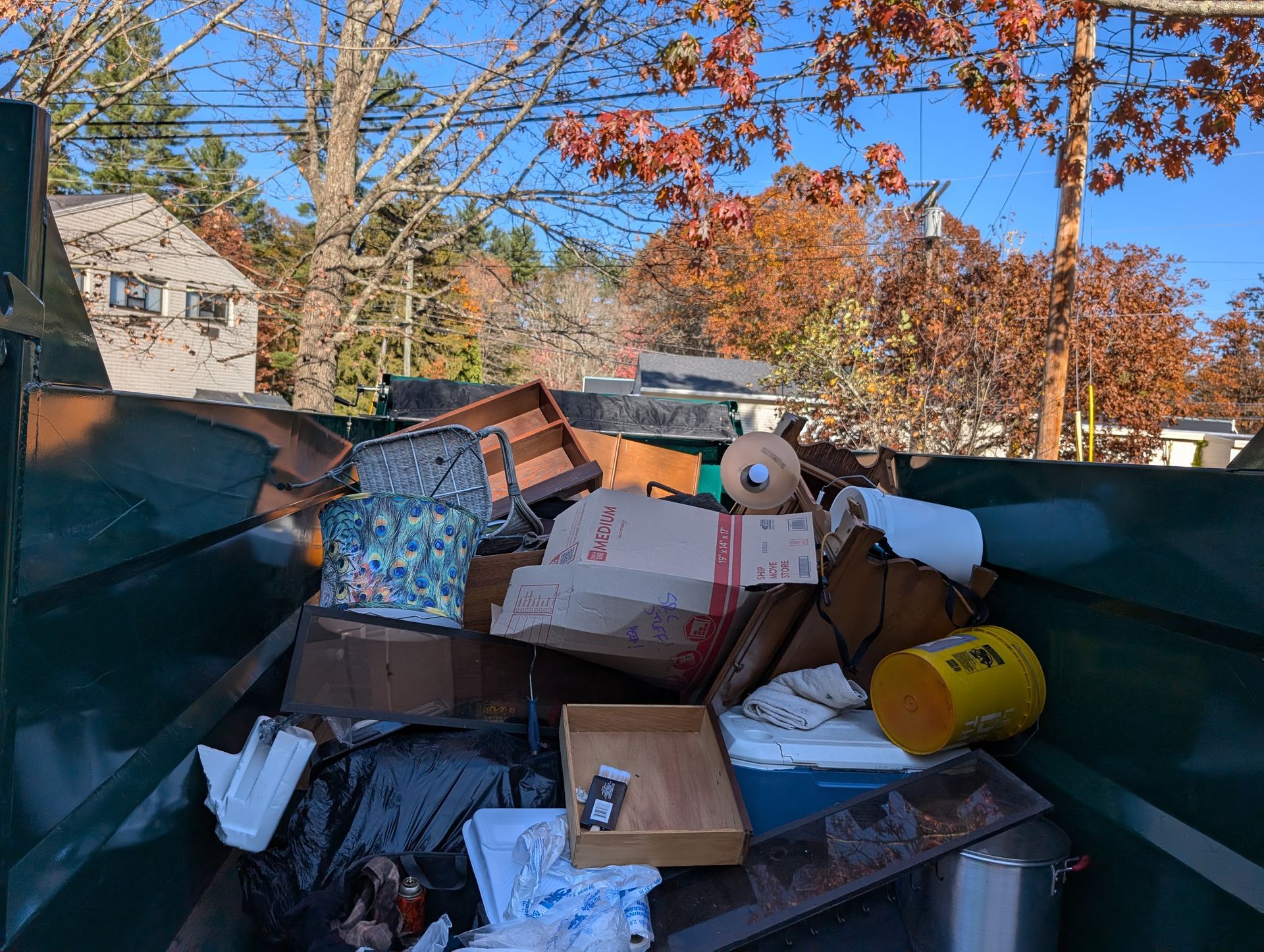 A dumpster filled with a lot of trash and boxes.