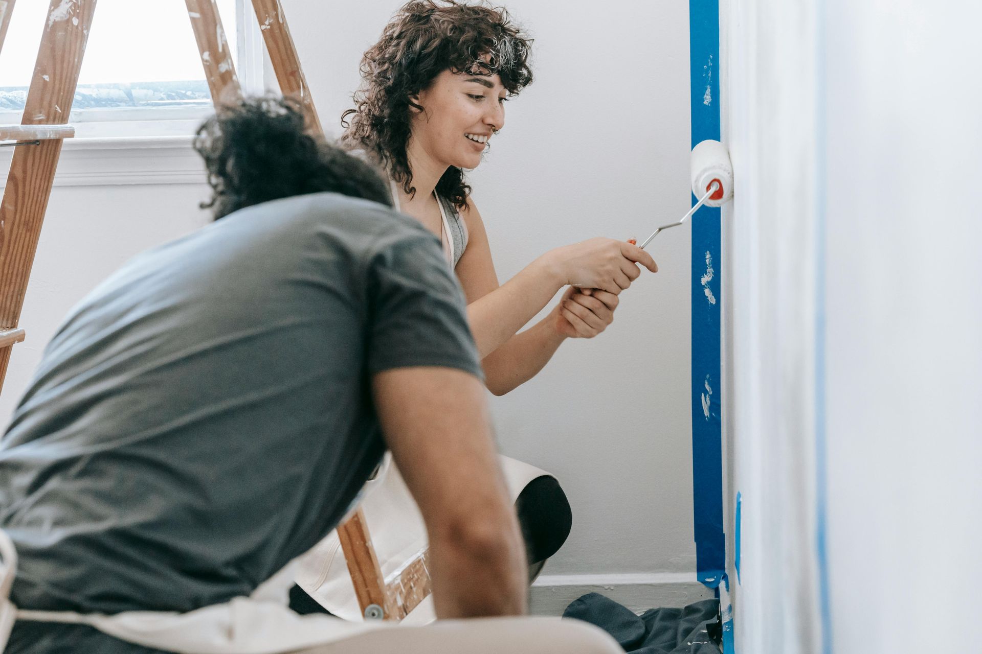 A man and a woman are painting a wall together.