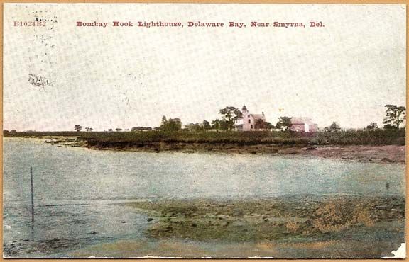 A vintage postcard view of Bombay Hook Lighthouse and its keeper's house overlooking a marshy Delaware Bay shoreline.