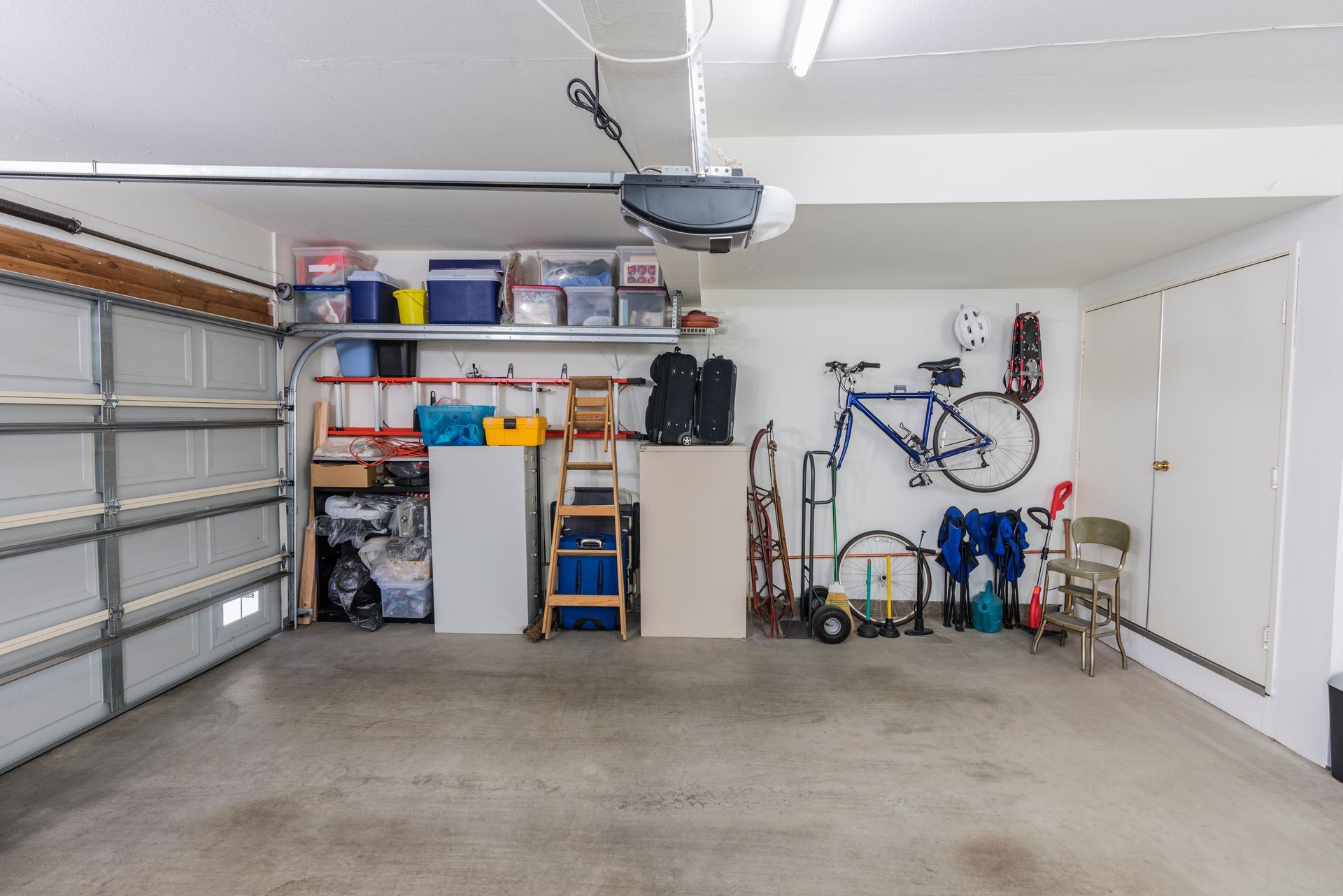 Clean garage interior with stored items, a bicycle, and a closed door.