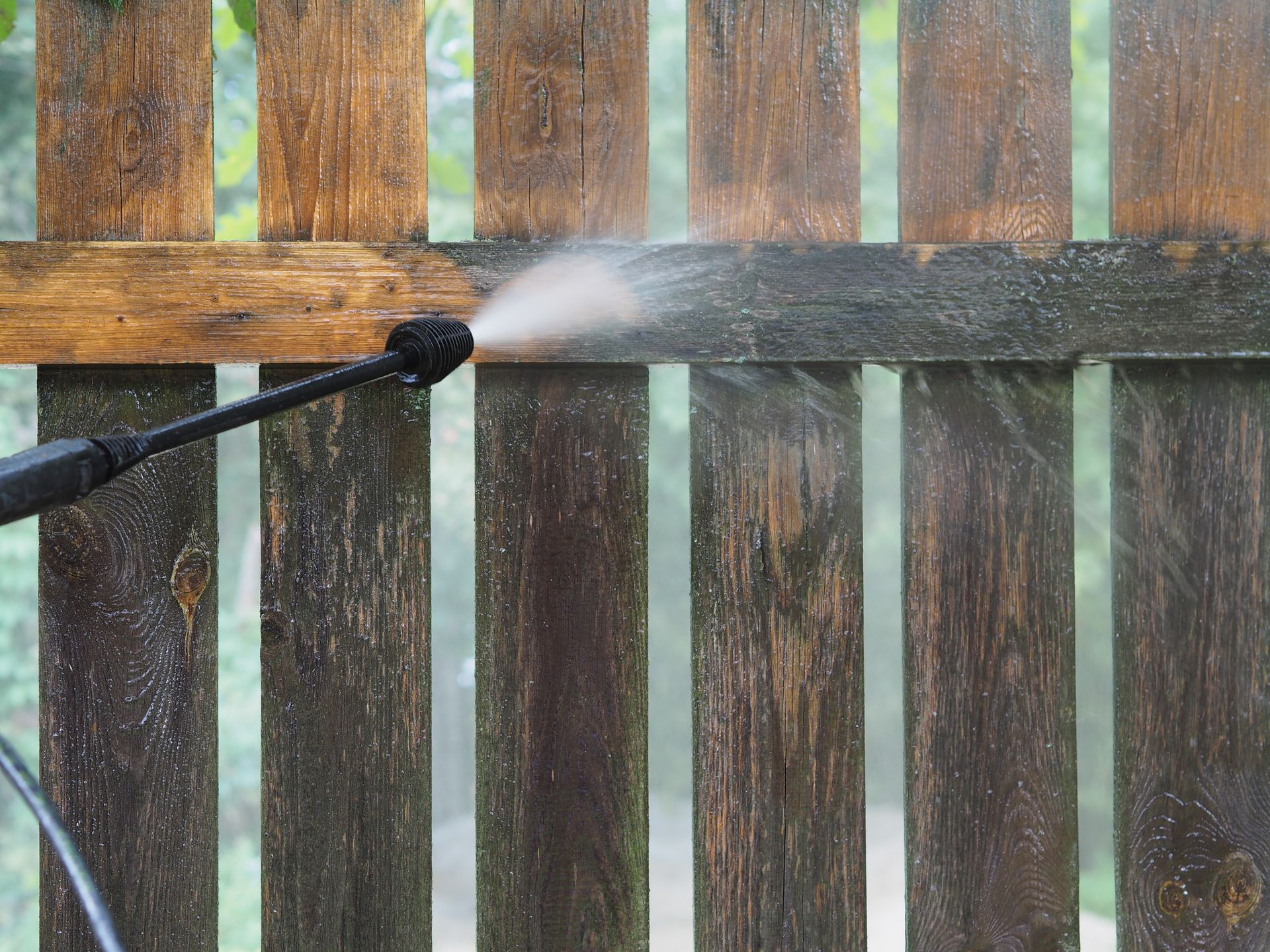 Pressure washer spraying a wooden fence, cleaning off dirt. Pressure washer spraying a wooden fence, cleaning off dirt.