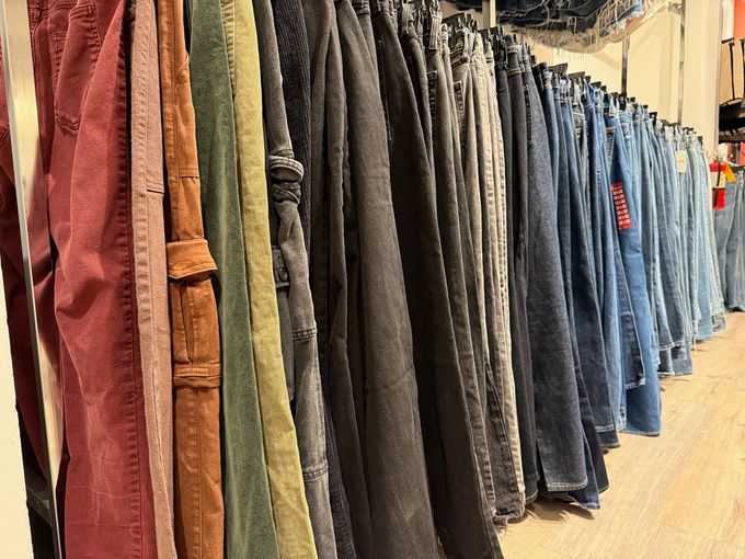 Clothing store rack with rows of jeans and pants in blue, gray, and tan tones