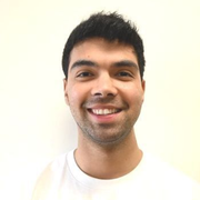 Smiling man with short dark hair against a plain light background