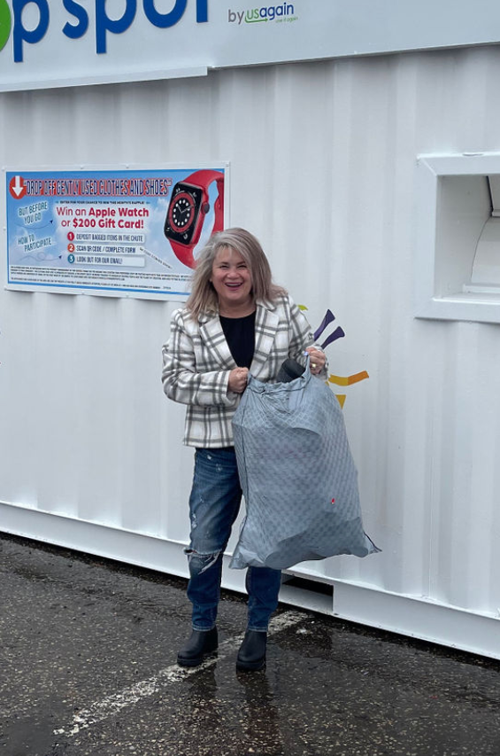 Woman holding a large bag in front of a white container building with a poster sign.