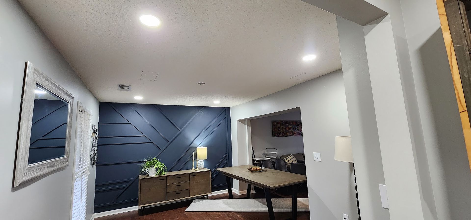 Modern living room with blue accent wall, couch, coffee table, and warm recessed lighting