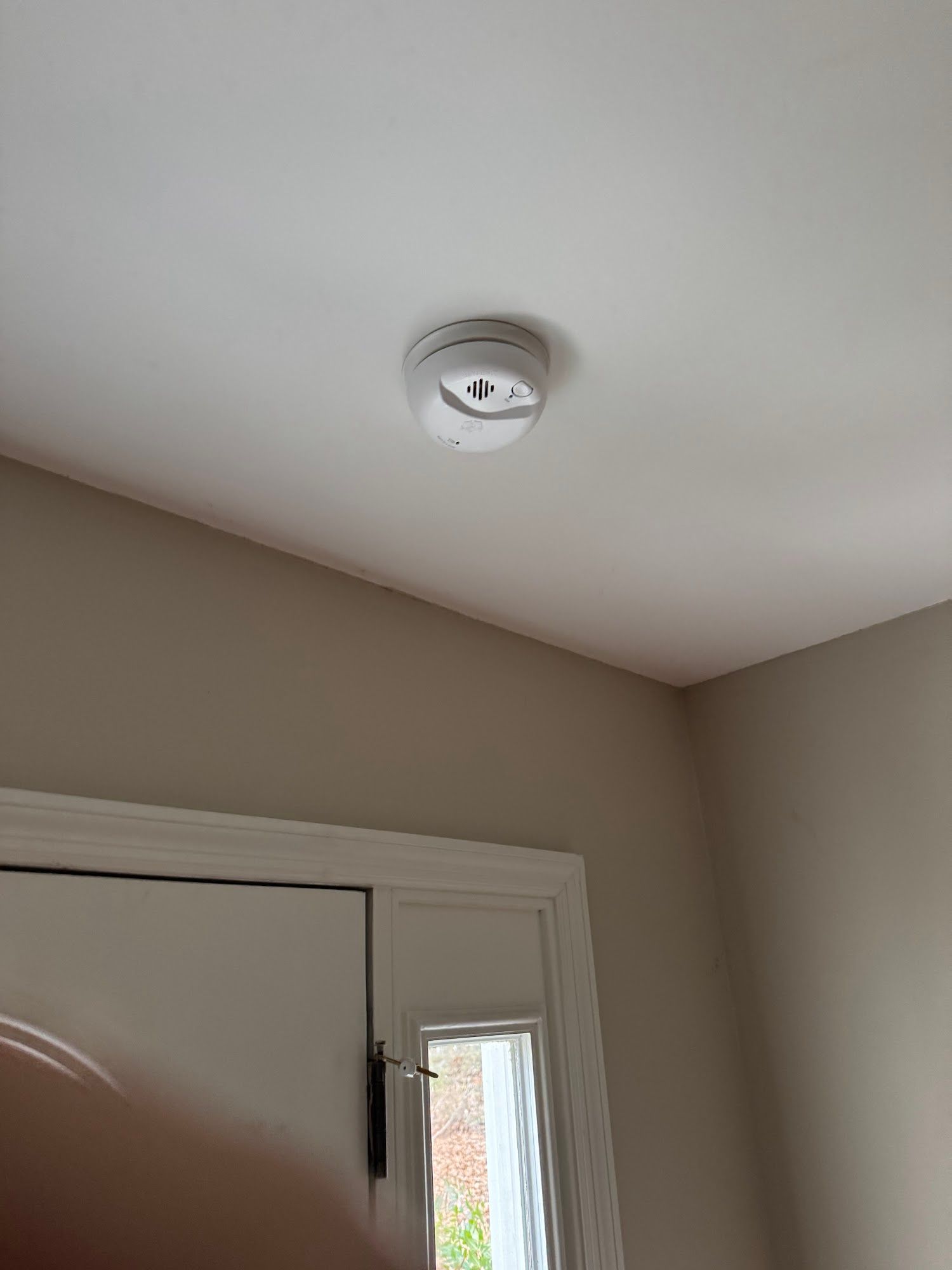 White ceiling smoke detector above a doorway in a beige room