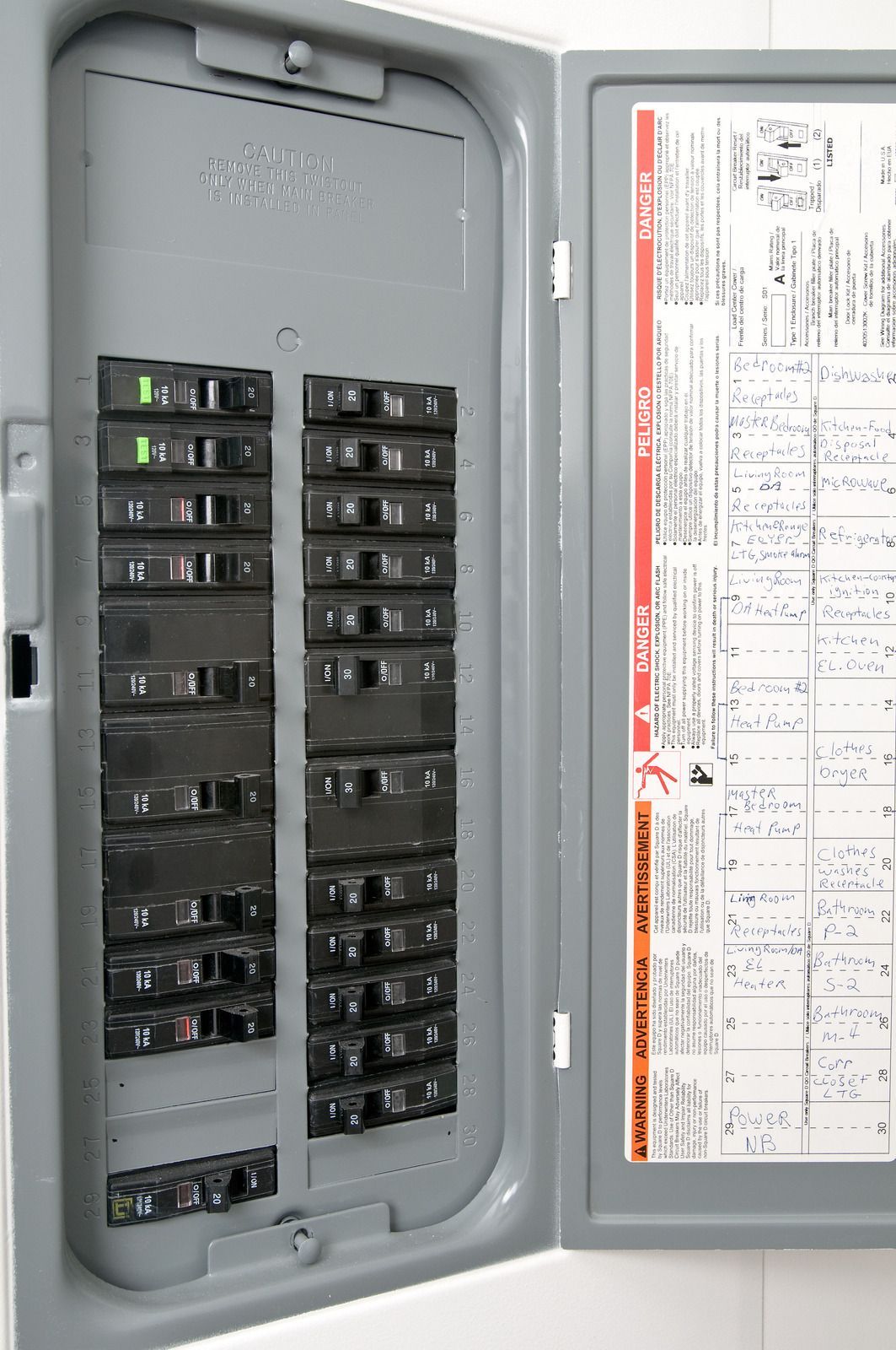 Open electrical breaker panel with rows of black switches and a circuit directory on the door