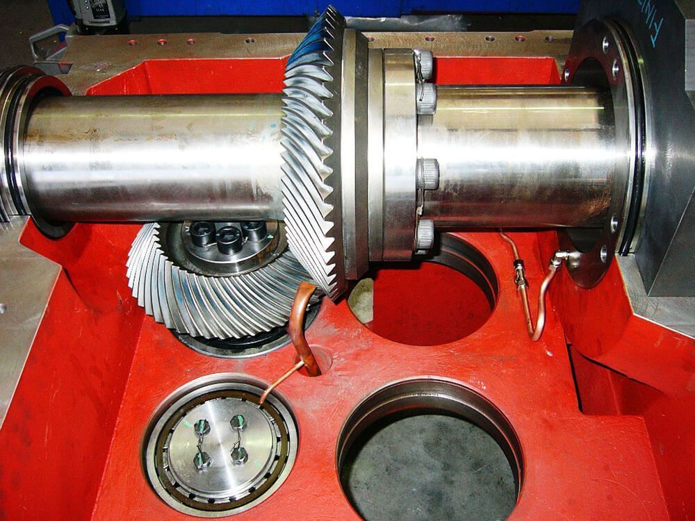 Primo piano dei componenti di macchinari industriali, tra cui ingranaggi e cuscinetti, all'interno di un involucro rosso.