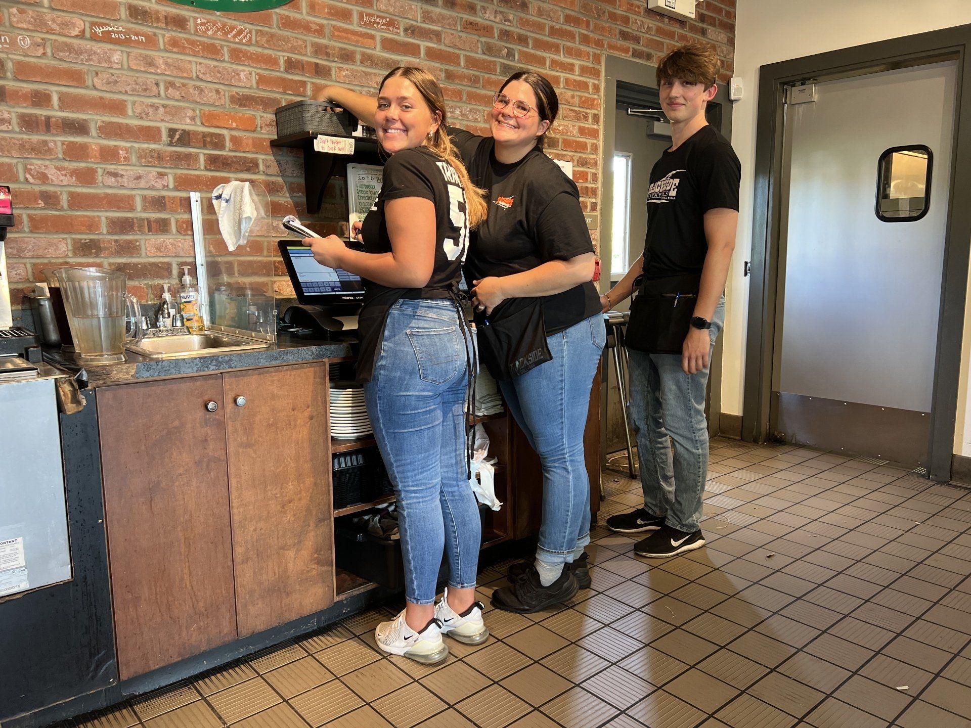 Three people are standing next to each other in a restaurant.