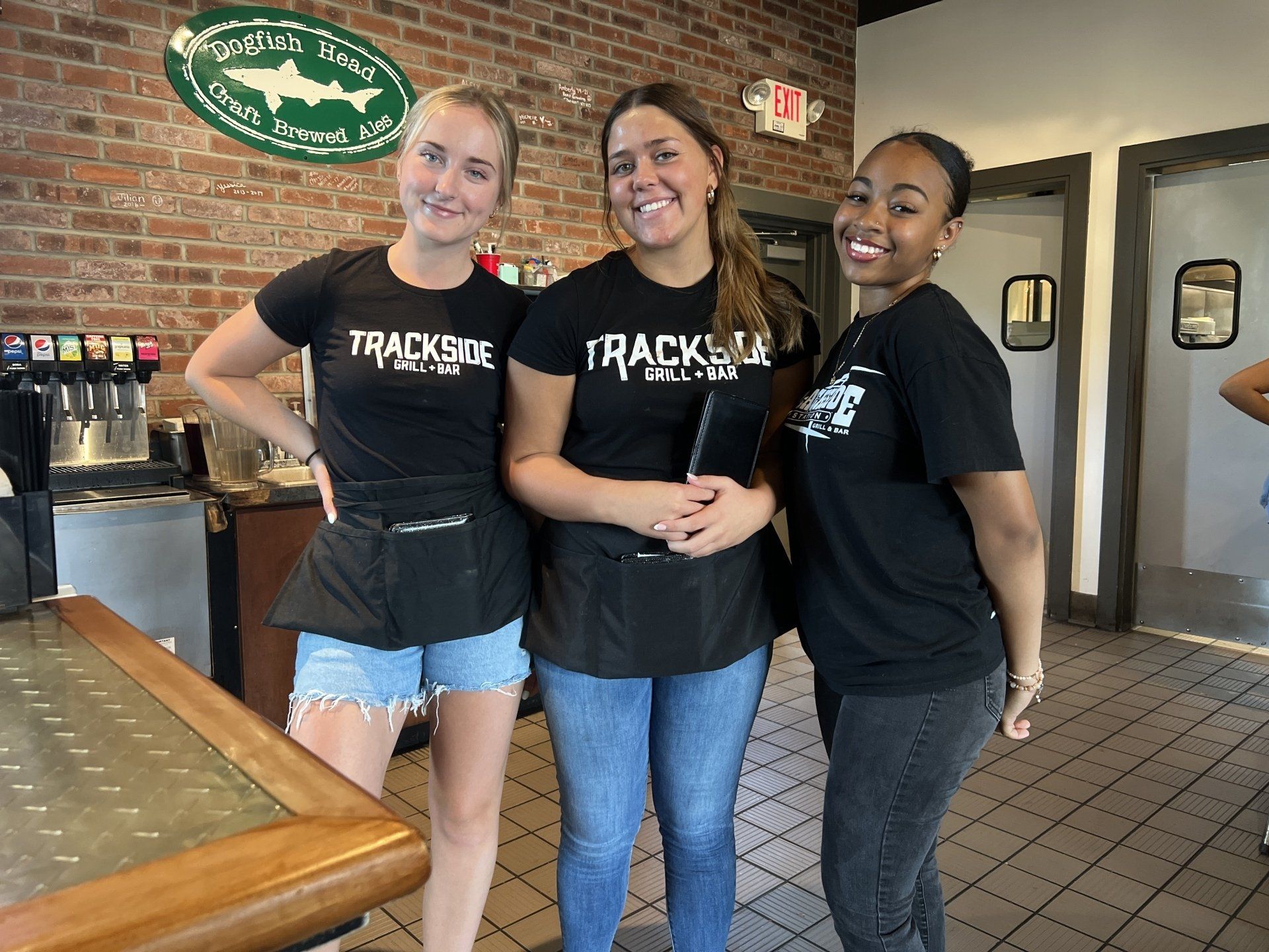 Three waitresses are posing for a picture in a restaurant.